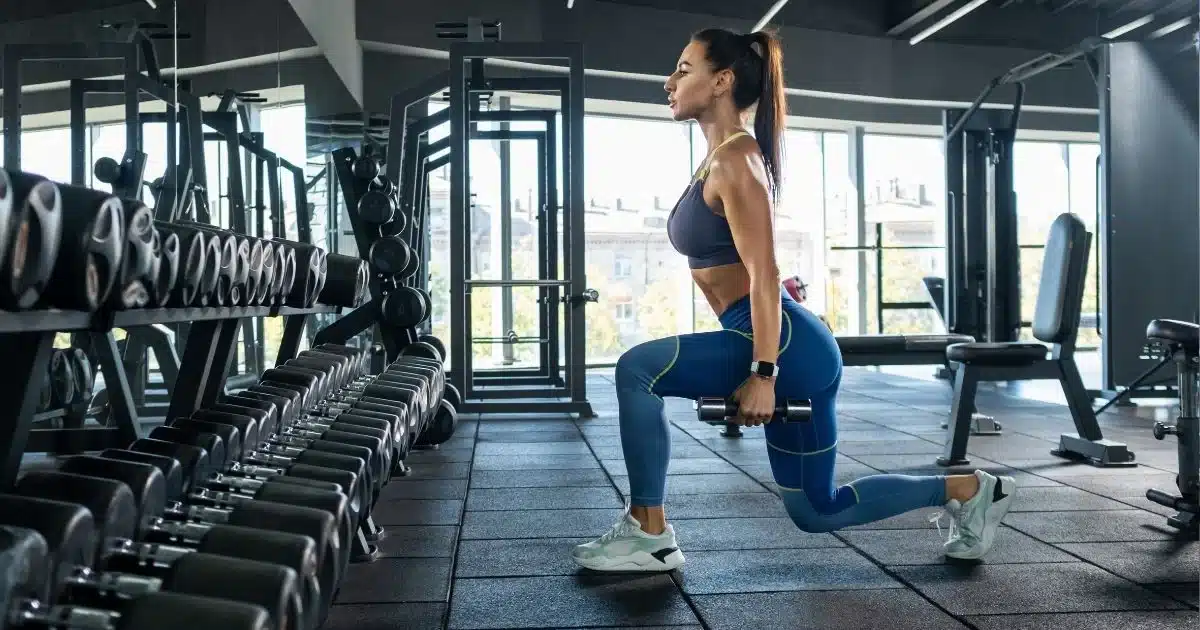 Fit Woman Doing A Dumbbell Lunge In The Gym